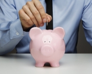 Male hand putting coin into a piggy bank